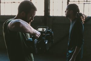 Man producing video with cast member. 